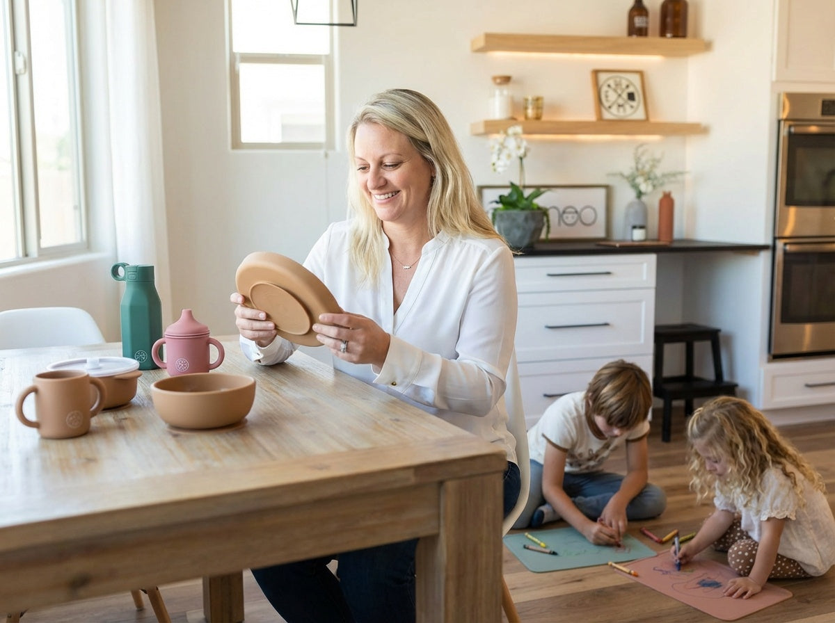 A woman holding Miminoo silicone dinnerware while her kids are playing in the minimalist scandinavian style kitchen