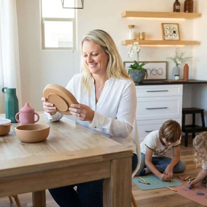 A woman holding Miminoo silicone dinnerware while her kids are playing in the minimalist scandinavian style kitchen