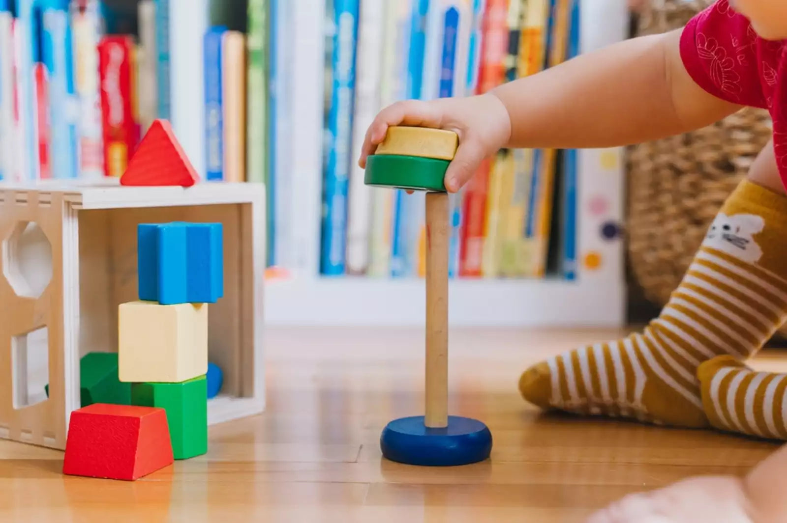 A toddler’s hands playing with a wooden Montessori toy.
