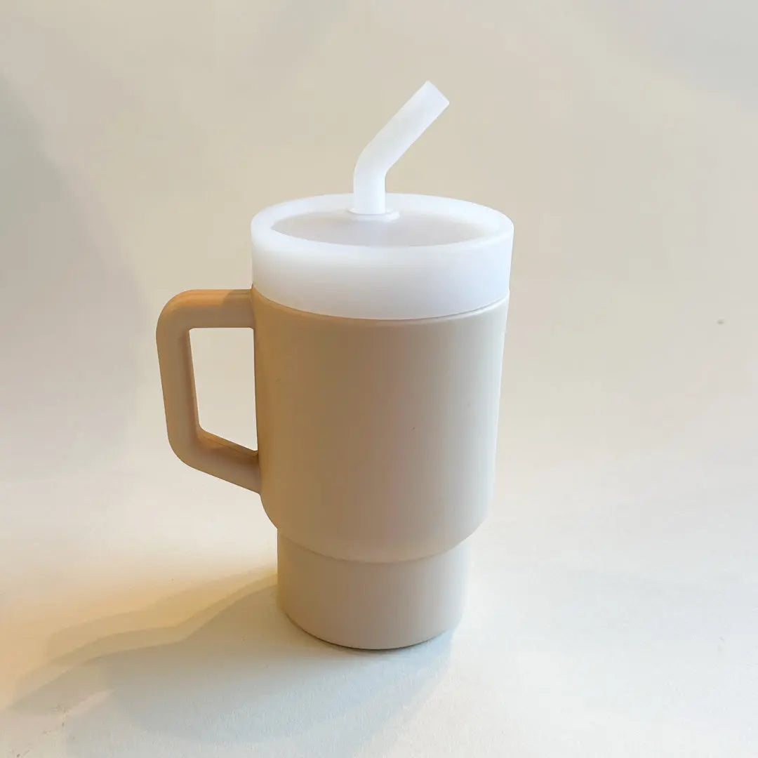 A lightweight 9oz toddler tumbler in soft, premium silicone, designed with a handle for easy grip and portability. The tumbler features a leak-resistant straw with a soft silicone tip, making it perfect for independent sipping. Beige unisex cup. Available in playful colors for kids, it combines functionality with fun for little explorers.