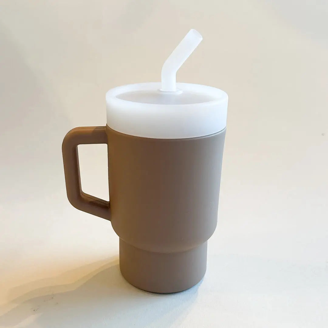 A lightweight 9oz toddler tumbler in soft, premium silicone, designed with a handle for easy grip and portability. The tumbler features a leak-resistant straw with a soft silicone tip, making it perfect for independent sipping. Available in playful colors for kids, it combines functionality with fun for little explorers. Sand color, unisex and trendy.