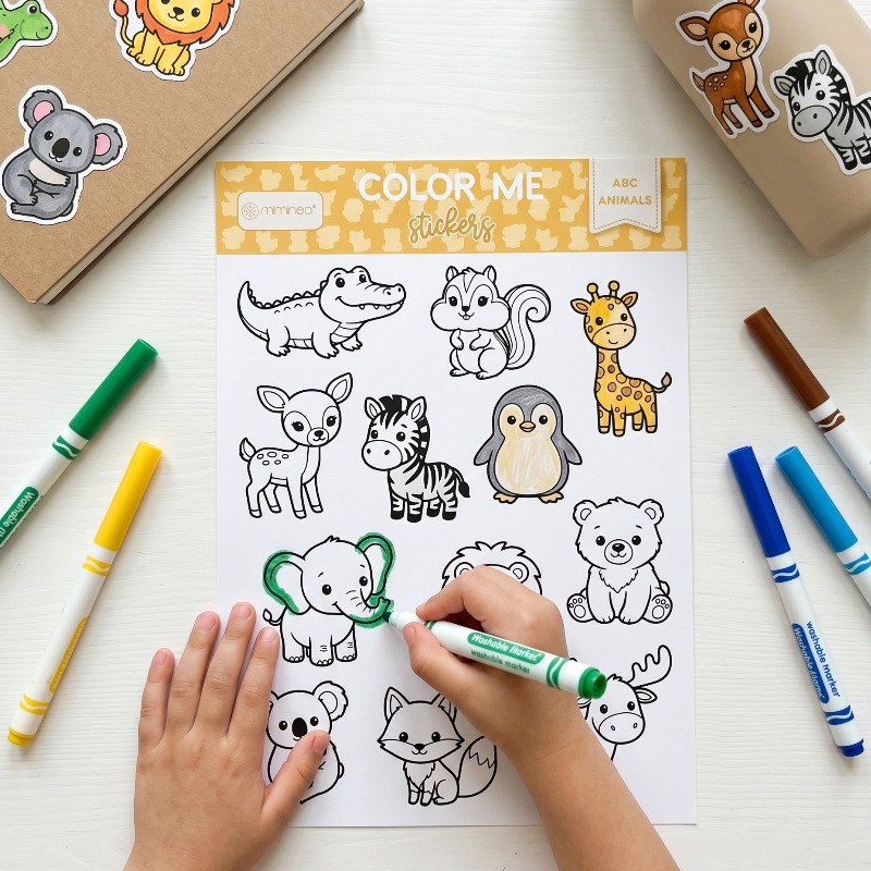 Coloring sheet with animal illustrations and markers on a white surface