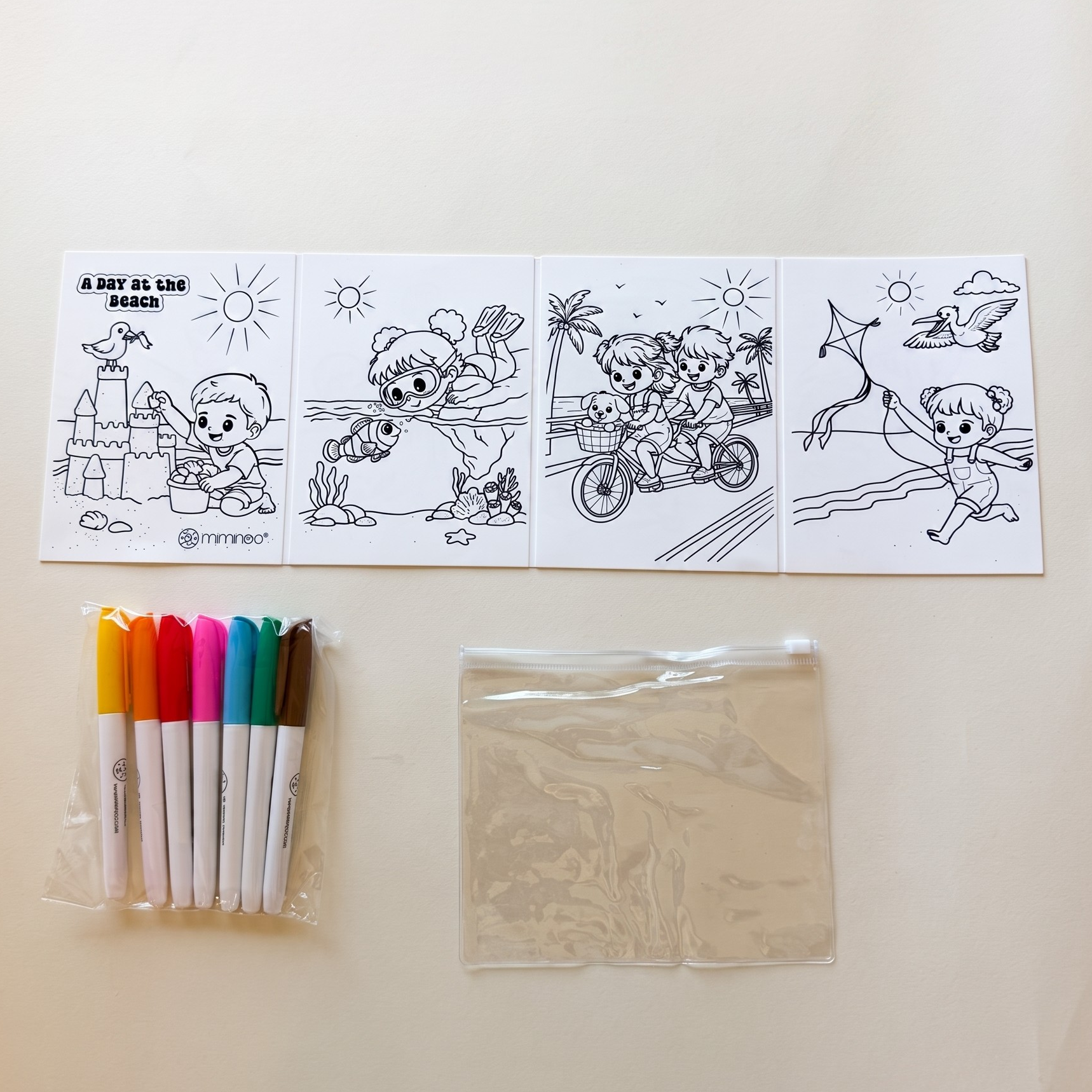A children's coloring kit laid out on a light beige surface, including four black-and-white cartoon activity panels, a pack of six colored markers, and a clear plastic bag containing paint or ink pads.