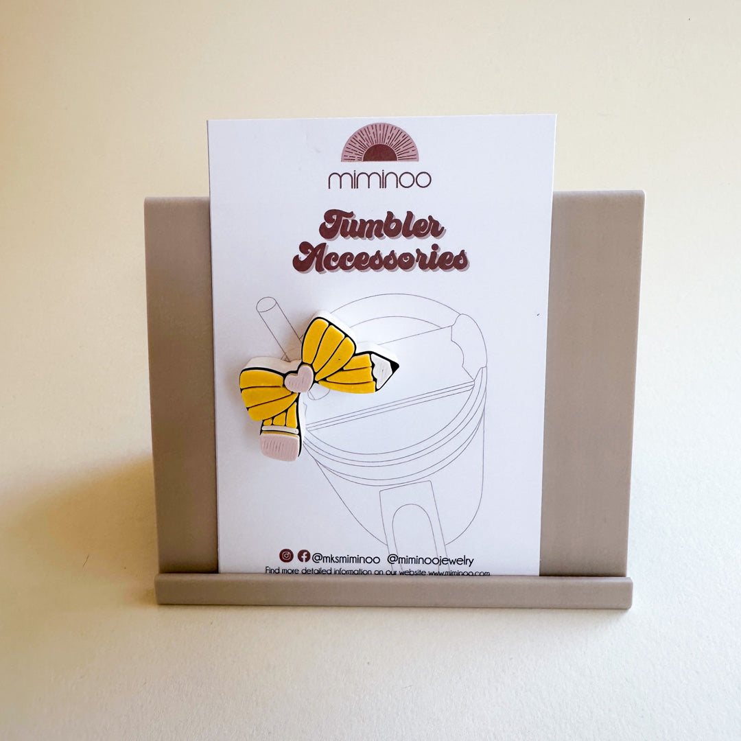 Yellow bow tumbler accessory on a card with 'mimimoo' branding.