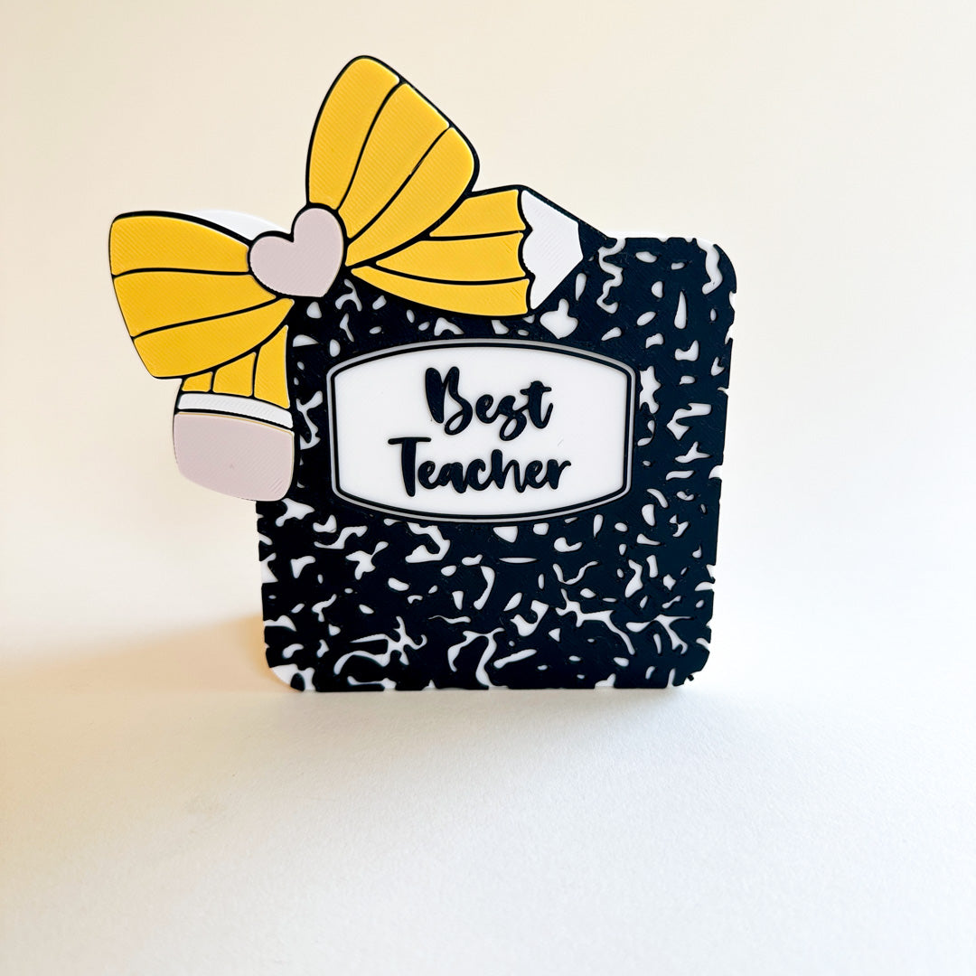 Decorative pen holder with a yellow bow and 'Best Teacher' label on a light background