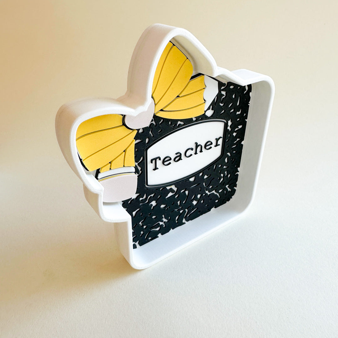 Decorative item shaped like a book with yellow leaves and 'Teacher' text on a light background